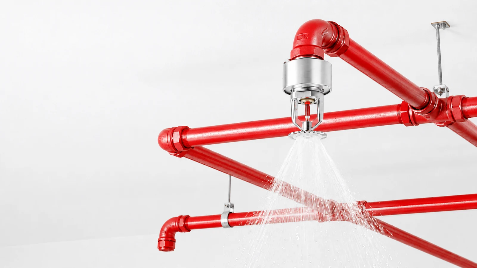 Red fire-suppression pipework and an operating sprinkler.